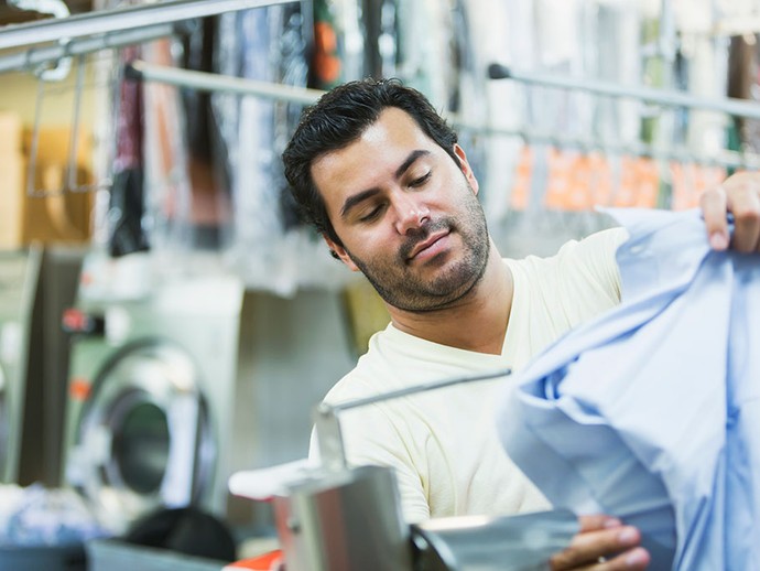 Ein Mann begutachtet in einer Wäscherei ein Hemd.